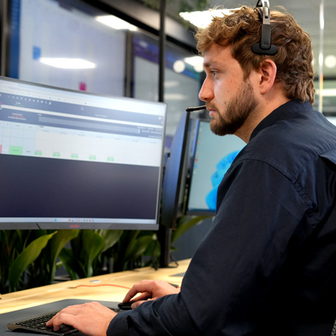 An operative with a headset working at his computer