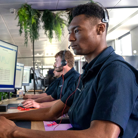 An operative with his headset on focused working at his computer