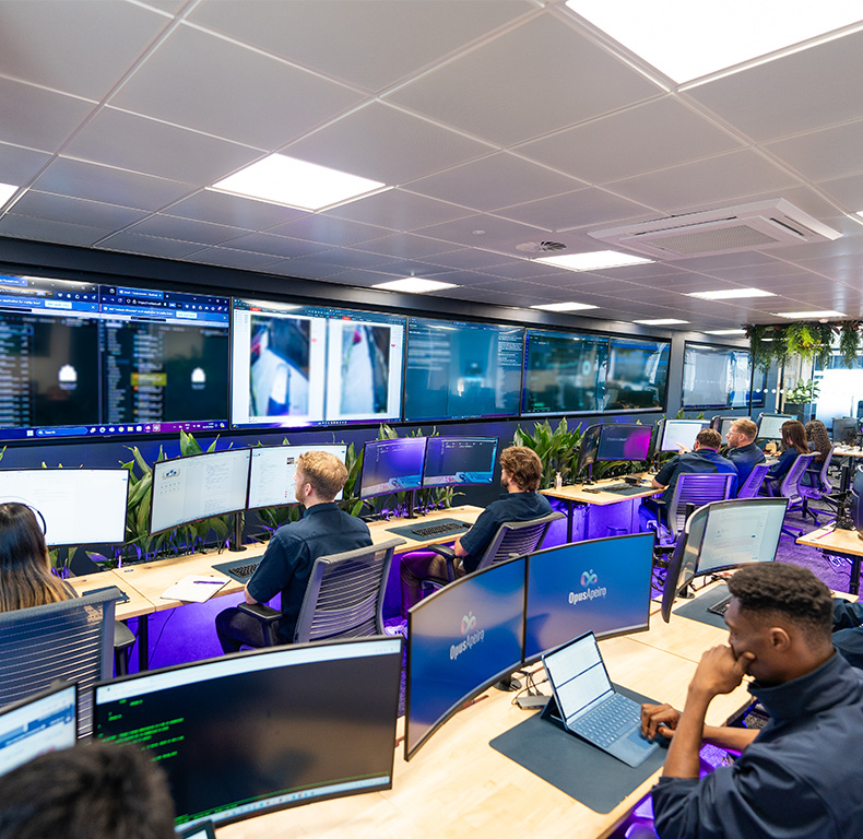 Operatives sat working at their computers with a wall of screens in front of them.